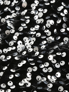 Macro view of high-density silver sequins stitched on black velvet fabric for evening dress