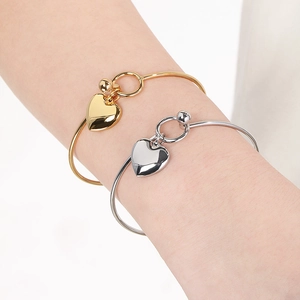 Close-up of gold and silver heart pendant bracelets worn on wrist with polished finish