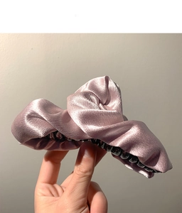 Dettaglio ravvicinato di un fermaglio per capelli in raso rosa antico da donna