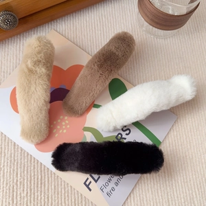 Close-up of four plush faux fur hair clips in beige, white, black and brown colors