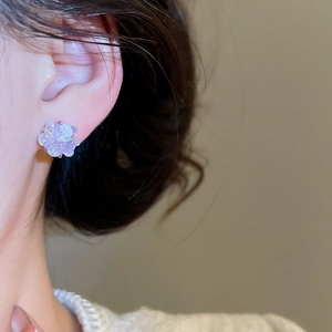 Close-up of elegant purple floral stud earrings with intricate layered petals on a model