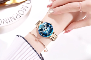Close-up of women's rose gold watch with faceted blue starry dial and jewelry set