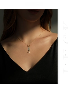 Close-up of S925 silver necklace featuring a pearl and green crystal pendant on neck