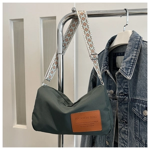 Detail of army green nylon crossbody bag with geometric wide strap and fashion leather patch
