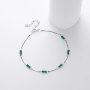 Macro view of 925 silver box chain bracelet with emerald green rectangular gemstones