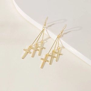 Close-up of triple gold cross drop earrings with elegant textured metal details