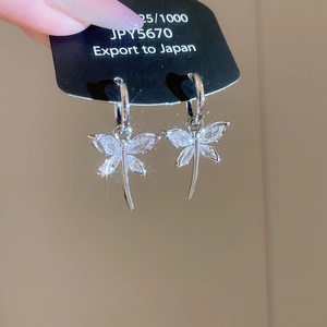 Detail of silver dragonfly earrings with sparkling zircon wings on a black display card