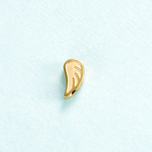 Macro shot of gold angel wing pendant with polished metal finish on blue texture