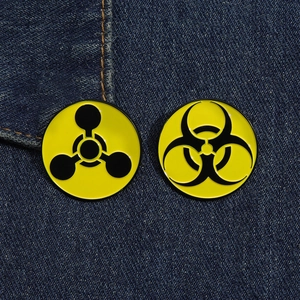 Macro shot of biohazard and radiation enamel pins on dark blue denim fabric background