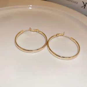 Minimalist polished golden hoop earrings displayed elegantly on a ceramic plate