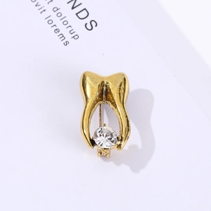 Creative gold tooth brooch pin with sparkling crystal gemstone on minimalist background