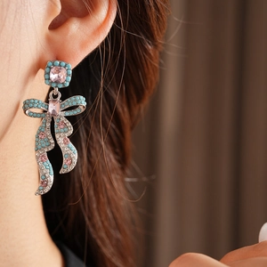 Gros plan de boucles d'oreilles nœud vintage avec perles turquoise et gemmes roses sur mannequin