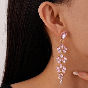 Close-up of pink crystal leaf earrings with gold-tone metal on an elegant model shot