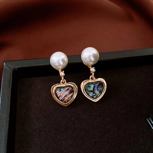 Gros plan de boucles d'oreilles cœur avec incrustations d'abalone et de perles