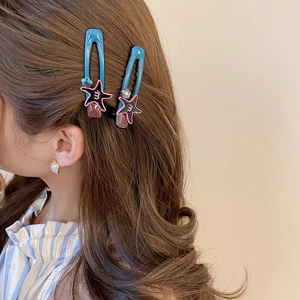Detail of blue acrylic hollow hair clips with star pattern on wavy brown hair