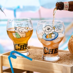 Close-up of glass beer cups with Bichon Frise patterns on a sunny beach background