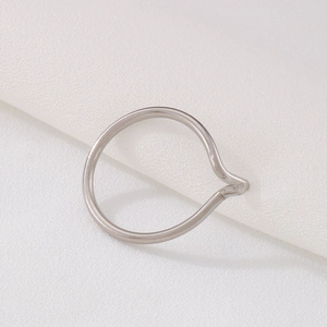 Close-up of minimalist silver stainless steel ring with a peak wave fold on white fabric