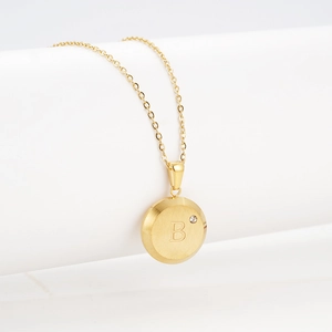 Detailed macro view of 18K gold letter B pendant necklace with a sparkling small zircon
