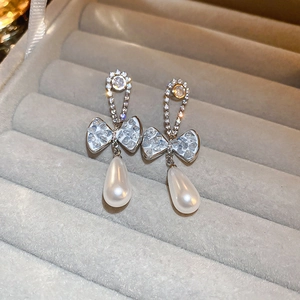 Detail of silver needle bow earrings with sparkling zircon and teardrop faux pearls