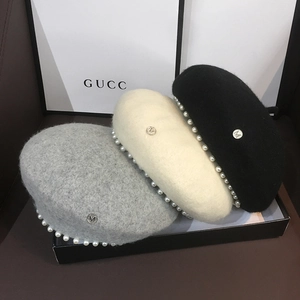 Detail view of wool beret hats with pearl trim and M metal logo in three neutral colors