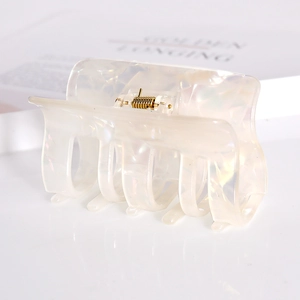 Macro detail of square acetate hair claw clip featuring creamy white pearl texture finish