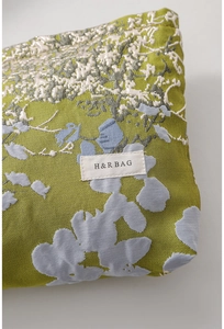 Close-up of green jacquard floral fabric and H&R BAG woven label on large cosmetic bag