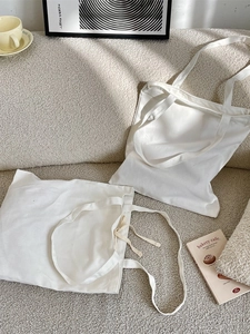 Minimalist white canvas tote bag with long handles on a beige sofa, spacious shoulder bag