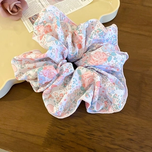 Gros plan détaillé d'un chouchou floral avec roses roses et fleurs bleues sur un plateau