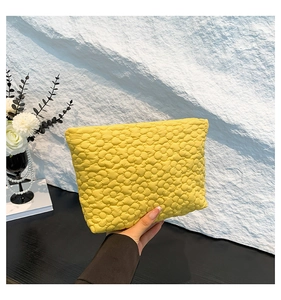 Close-up of a hand holding the yellow quilted floral makeup bag showing fabric texture