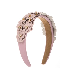 Detail of pink floral headband with layered petals and sparkling yellow rhinestones