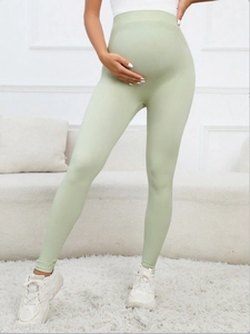 Detail of high-waist maternity leggings in light green ribbed fabric for a cozy look