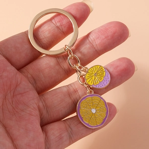 Close-up of golden fruit charms with purple and yellow enamel on a keychain
