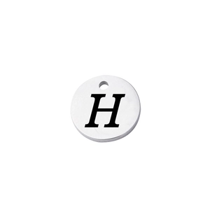 Macro detail of a mirror-polished stainless steel round pendant with engraved letter H