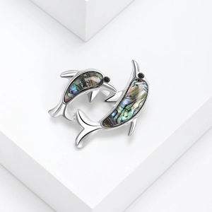 Silver dolphin stud earrings with iridescent abalone shell inlay on white platform