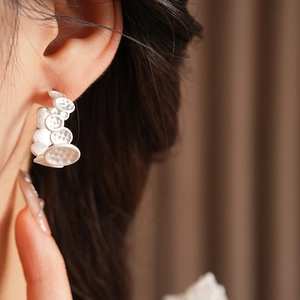 Gros plan d'une boucle d'oreille créole blanche en C avec texture irrégulière