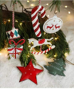 Close-up of hand-painted metal Christmas ornaments hanging on a snowy pine branch