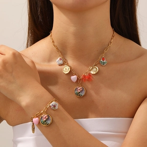 Detail of vintage gold-plated necklace with enamel flower and butterfly heart charms