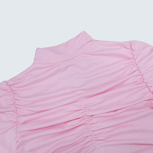 Détail de la robe rose à manches longues montrant le col montant et la texture froncée