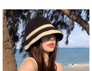 Detail of knitted bucket hat with black and beige stripes against a beach backdrop