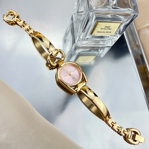 Detail of elegant gold bracelet watch with pink dial on a metallic display tray