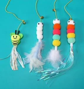 Detail of hanging cat toys set featuring bee, plush caterpillars, feathers and tassels
