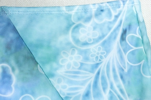 Close-up of blue floral mesh fabric with white leaf patterns and detailed double stitching