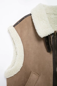 Detail of brown suede vest featuring white shearling lining and dark leather collar strap