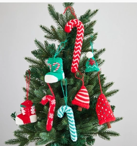 Close-up of handmade knitted Christmas tree ornaments featuring candy canes and socks