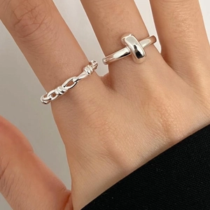 Detail shot of silver braided chain and geometric T-shape open rings set on a model hand
