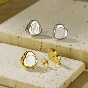 Detail of heart-shaped 18K gold and silver earrings with iridescent mother of pearl inlay