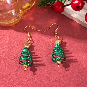 Macro detail of Christmas tree earrings with gold stars on a festive red background