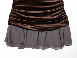 Detail van fluwelen geplooid lijfje met grijze chiffon ruches aan de zoom van de jurk