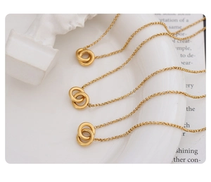Polished gold plated titanium steel interlocking ring necklaces on a white decorative dish