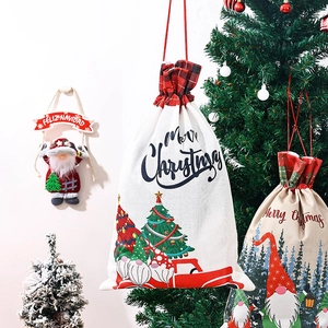 Close-up of fabric Christmas drawstring bags with gnome and truck prints on a holiday tree